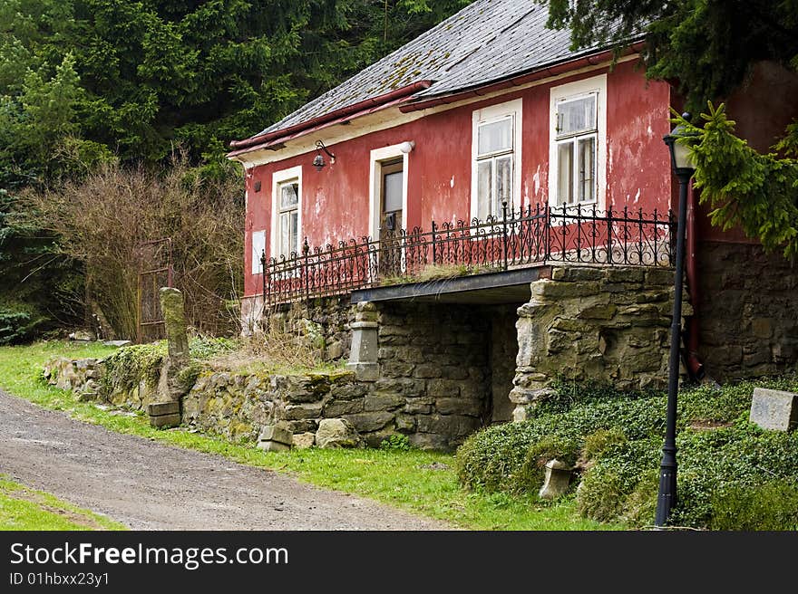 Old red impaired house with white windows and iron rail on the stone wall. Old red impaired house with white windows and iron rail on the stone wall