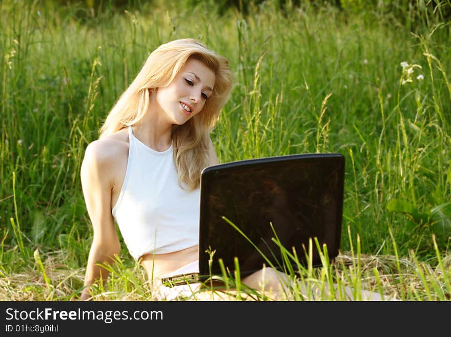 Pretty blonde with a laptop in grass. Pretty blonde with a laptop in grass