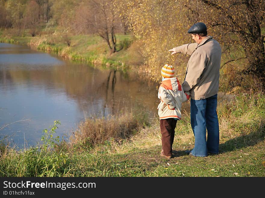 Grandfather with grandson in wood look on water