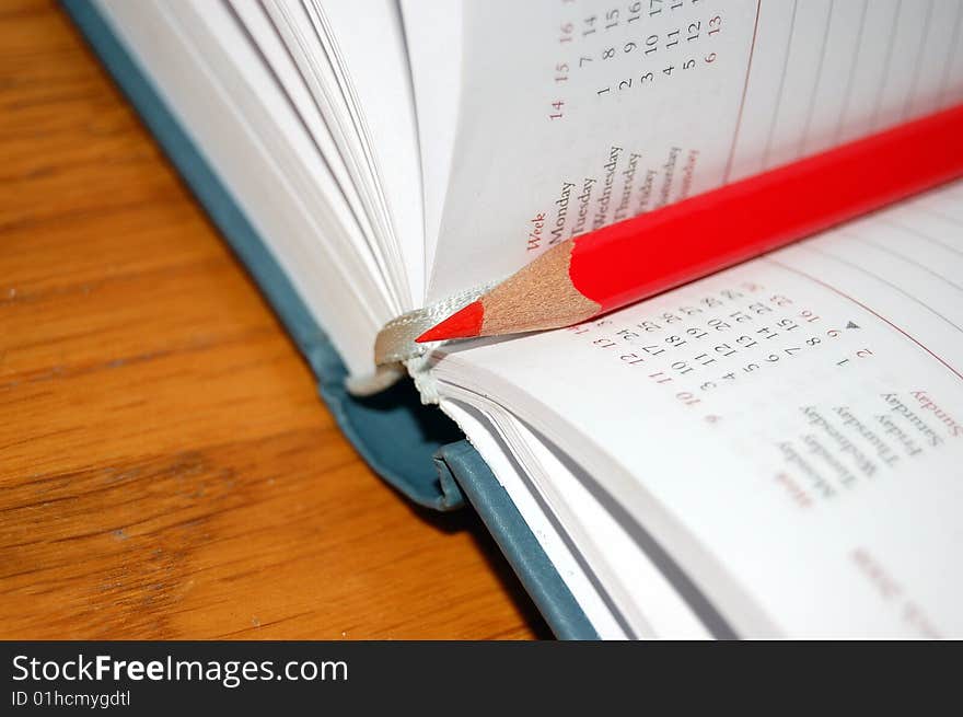 Open diary with red pencil on writing table