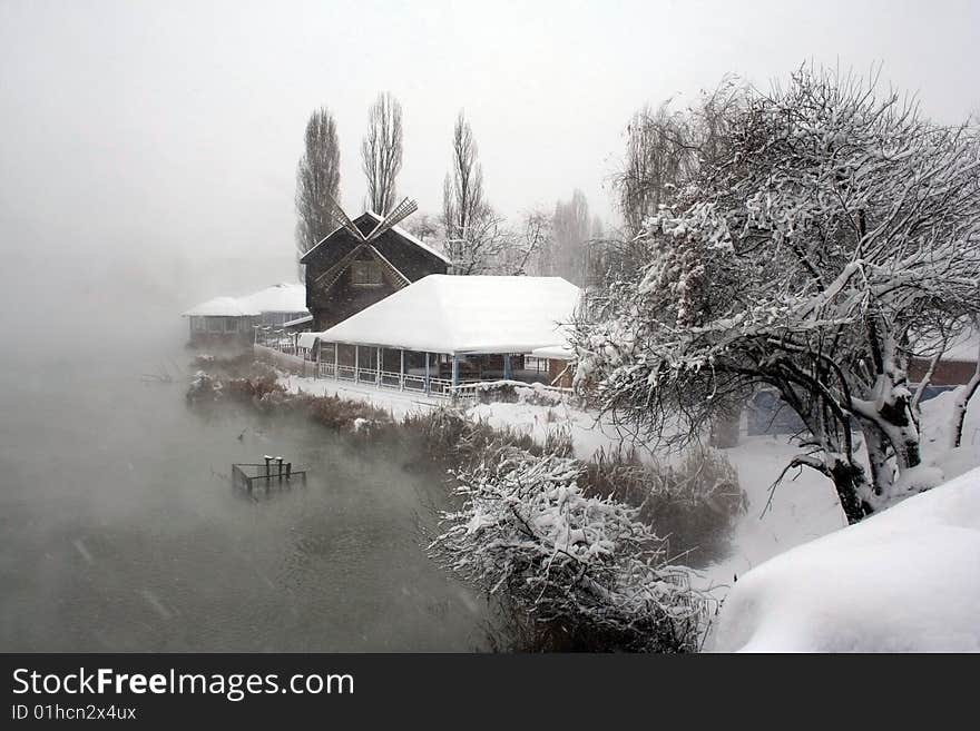 The Strong snow.The Tree and bulrushes in snow on river.The Type with bridge on mill and river. The Strong snow.The Tree and bulrushes in snow on river.The Type with bridge on mill and river.