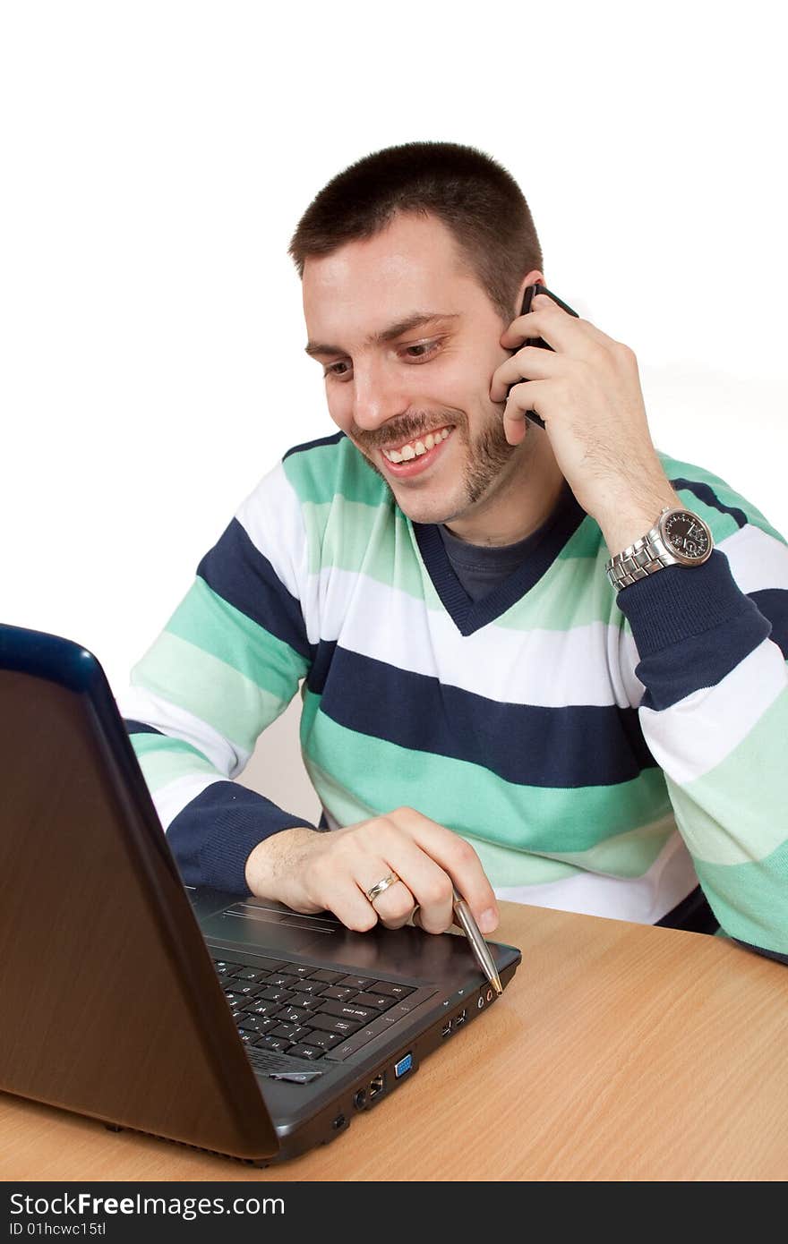 Young man working with his notebook and talking on mobile phone. Young man working with his notebook and talking on mobile phone