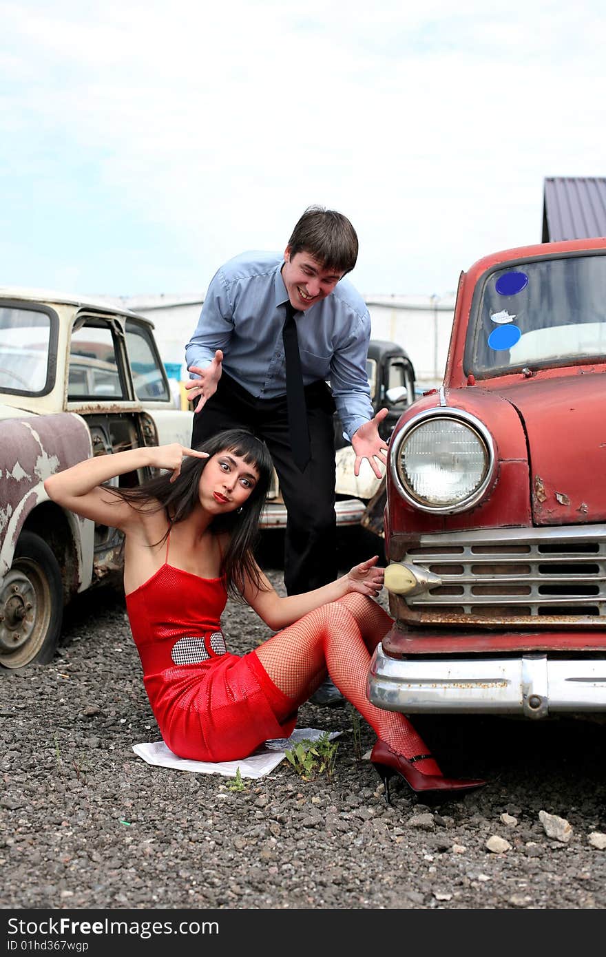 Girl and man beside retro car- under constructions to wheel