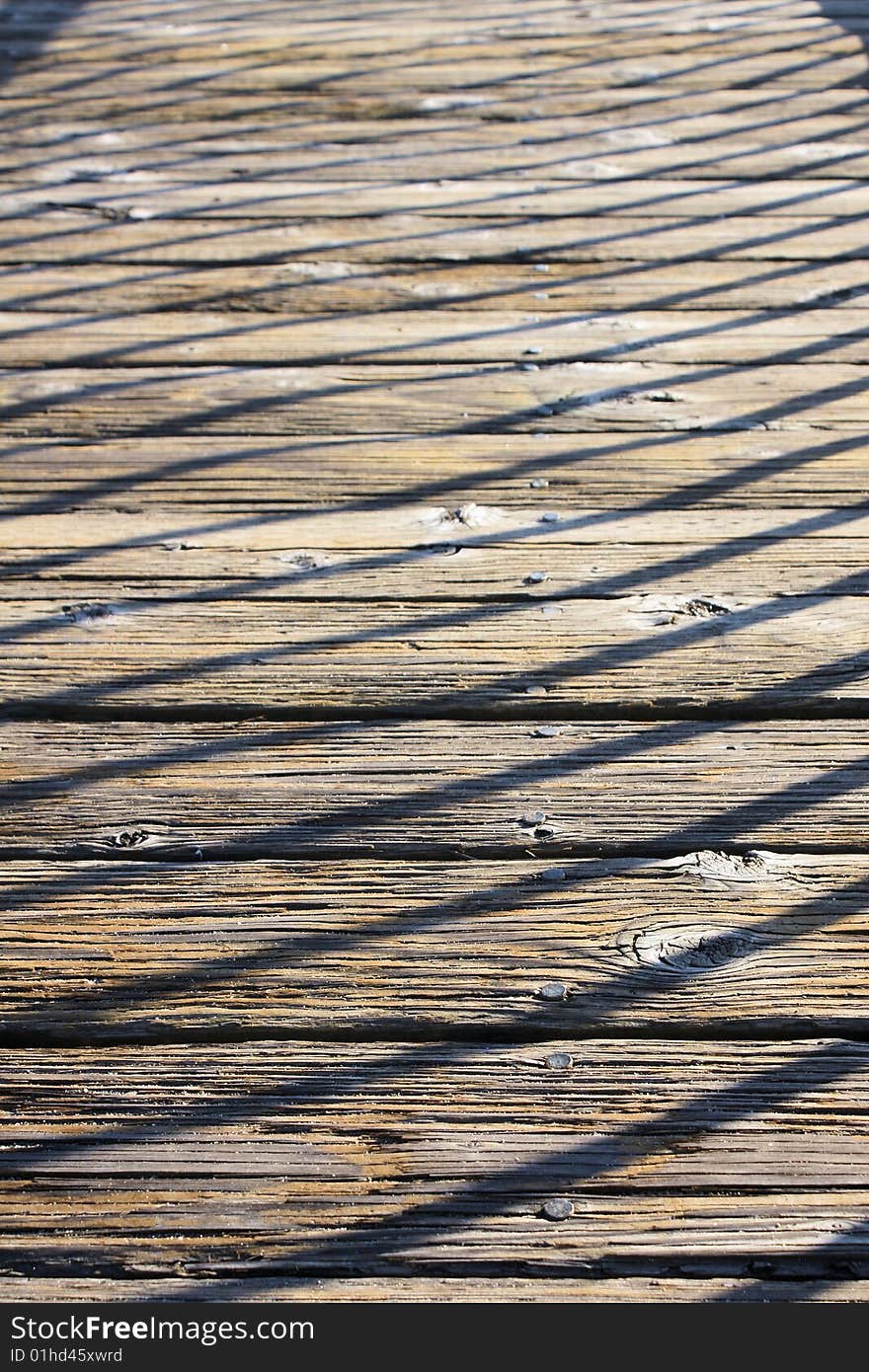 The shadow of a railing falling across a dock out on a lake. The shadow of a railing falling across a dock out on a lake.