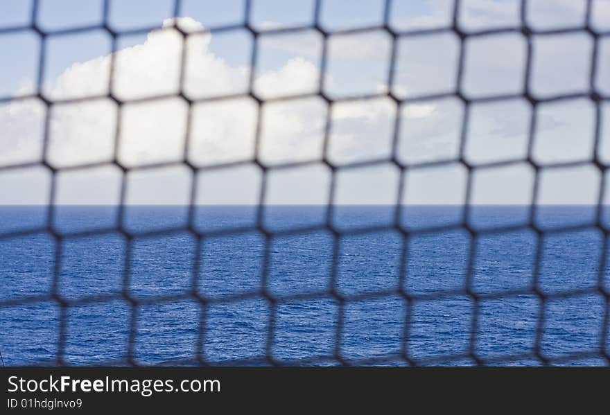 A rope mesh fence in front of the ocean. A rope mesh fence in front of the ocean