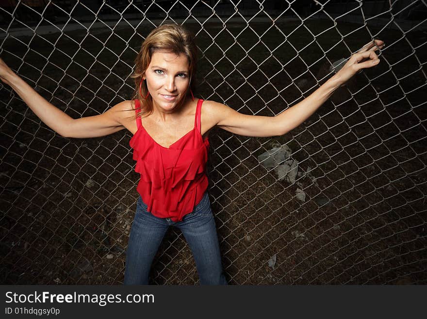 Beautiful woman posing on a fence. Beautiful woman posing on a fence