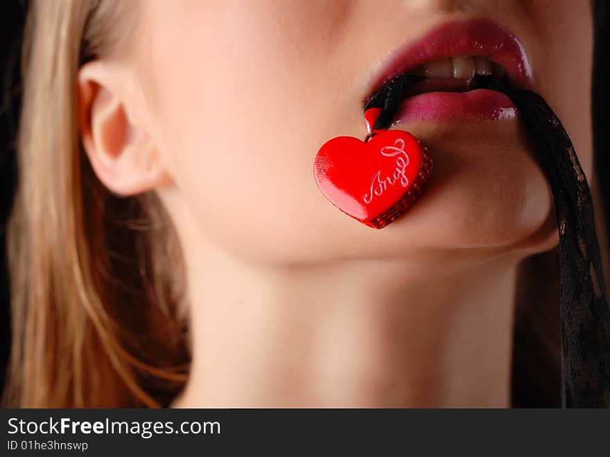 Young beautiful woman holding red heart in her mouth. Young beautiful woman holding red heart in her mouth