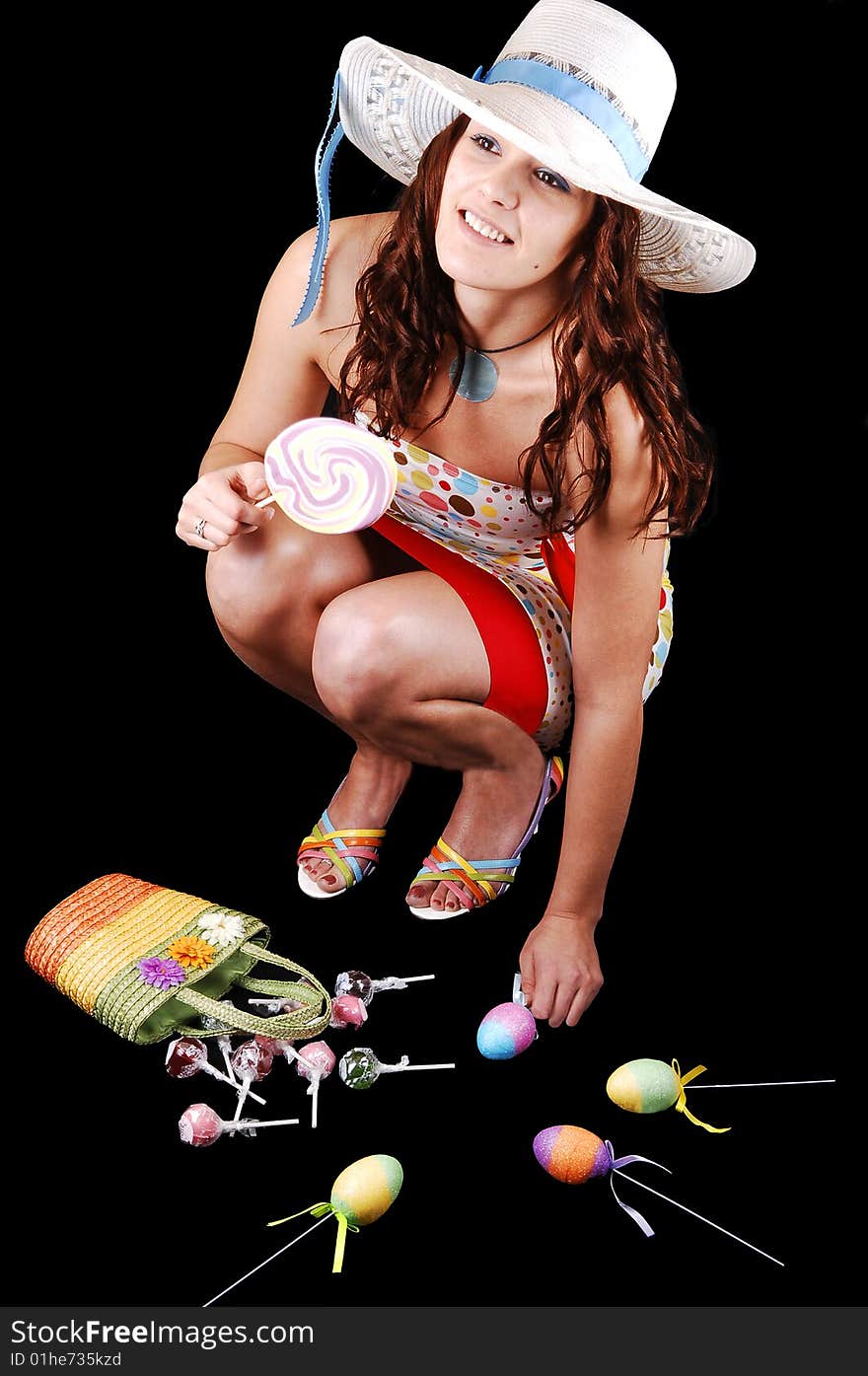 Lovely woman in an colorful dress and a white hat with eastern
eggs on the floor, over black background. Lovely woman in an colorful dress and a white hat with eastern
eggs on the floor, over black background.