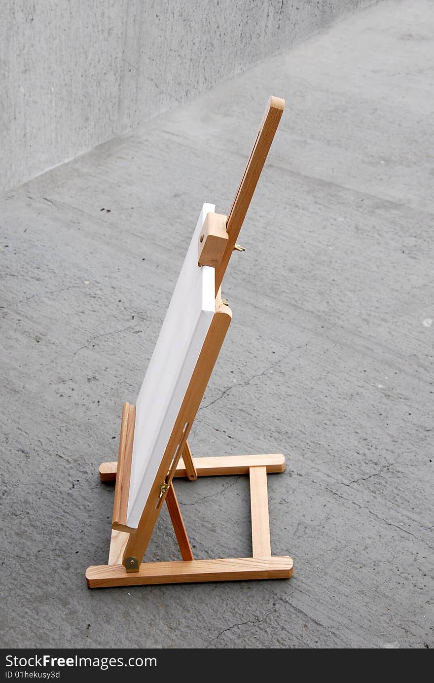 Easel with blank canvas on gray concrete background