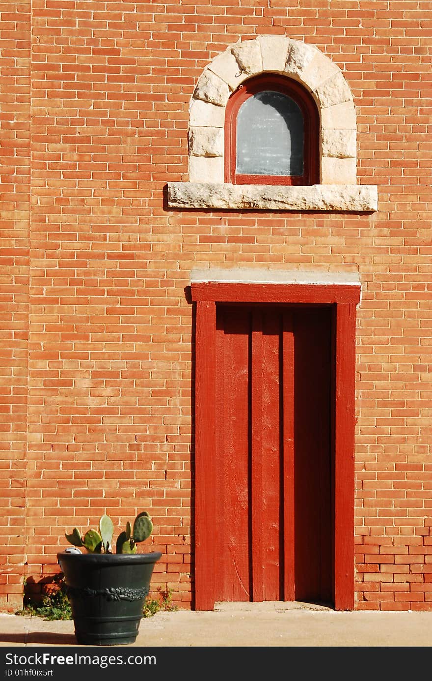 Rust door on brick building with cactus