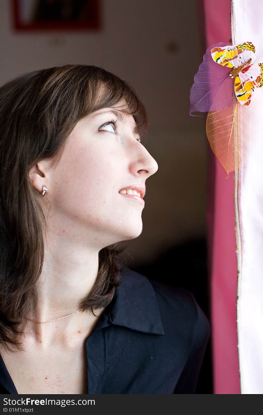 Beautiful girl looks at the bright butterfly on a pink curtains. Beautiful girl looks at the bright butterfly on a pink curtains