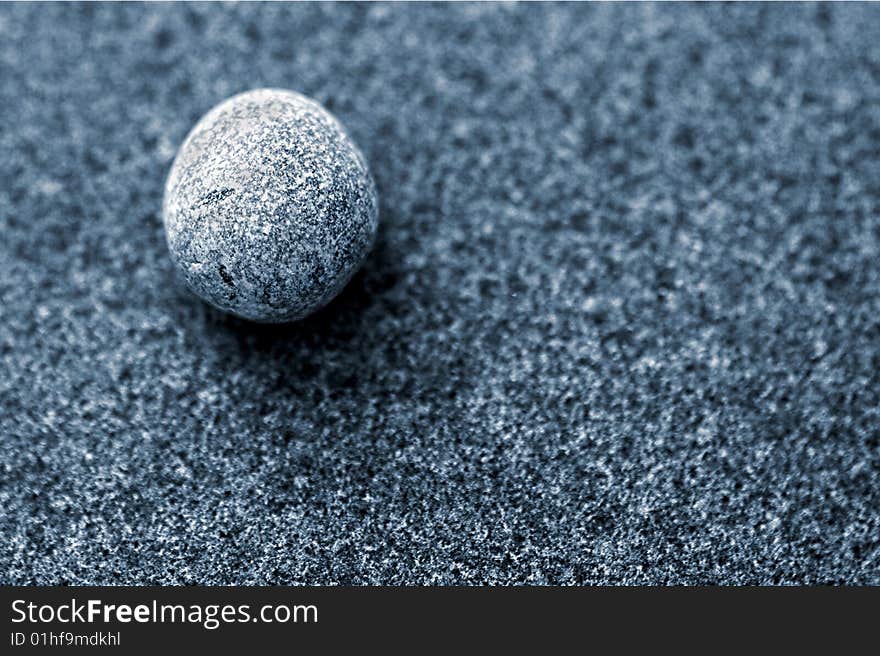 Small sliver coloured pebble on a larger blue toned pebble. Small sliver coloured pebble on a larger blue toned pebble.