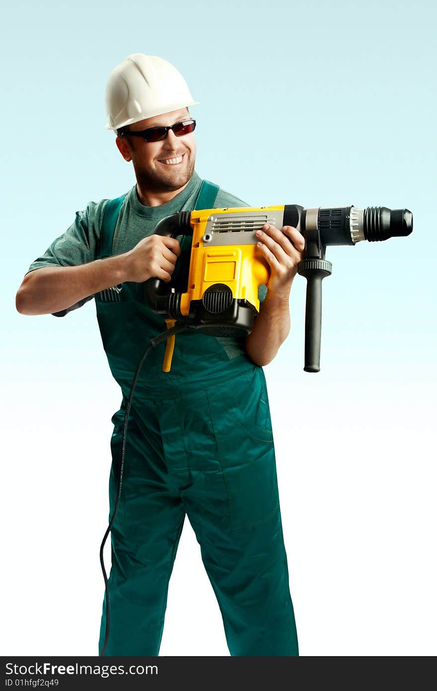 Smiled workman in helmet, black glasses and overalls hold perforator in his hands and drilled over white background. Smiled workman in helmet, black glasses and overalls hold perforator in his hands and drilled over white background