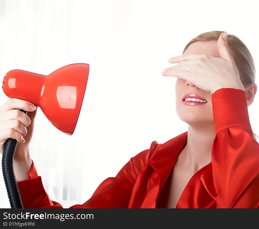 The beautiful girl in red holds a desk lamp in hands