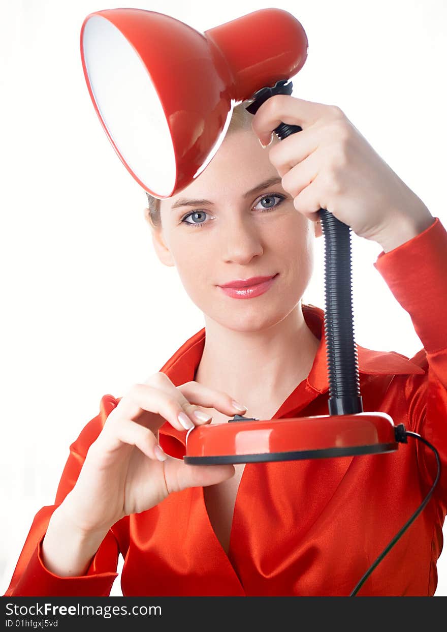 The beautiful girl in red holds a desk lamp in hands