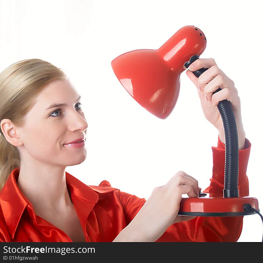 The beautiful girl in red holds a desk lamp in hands