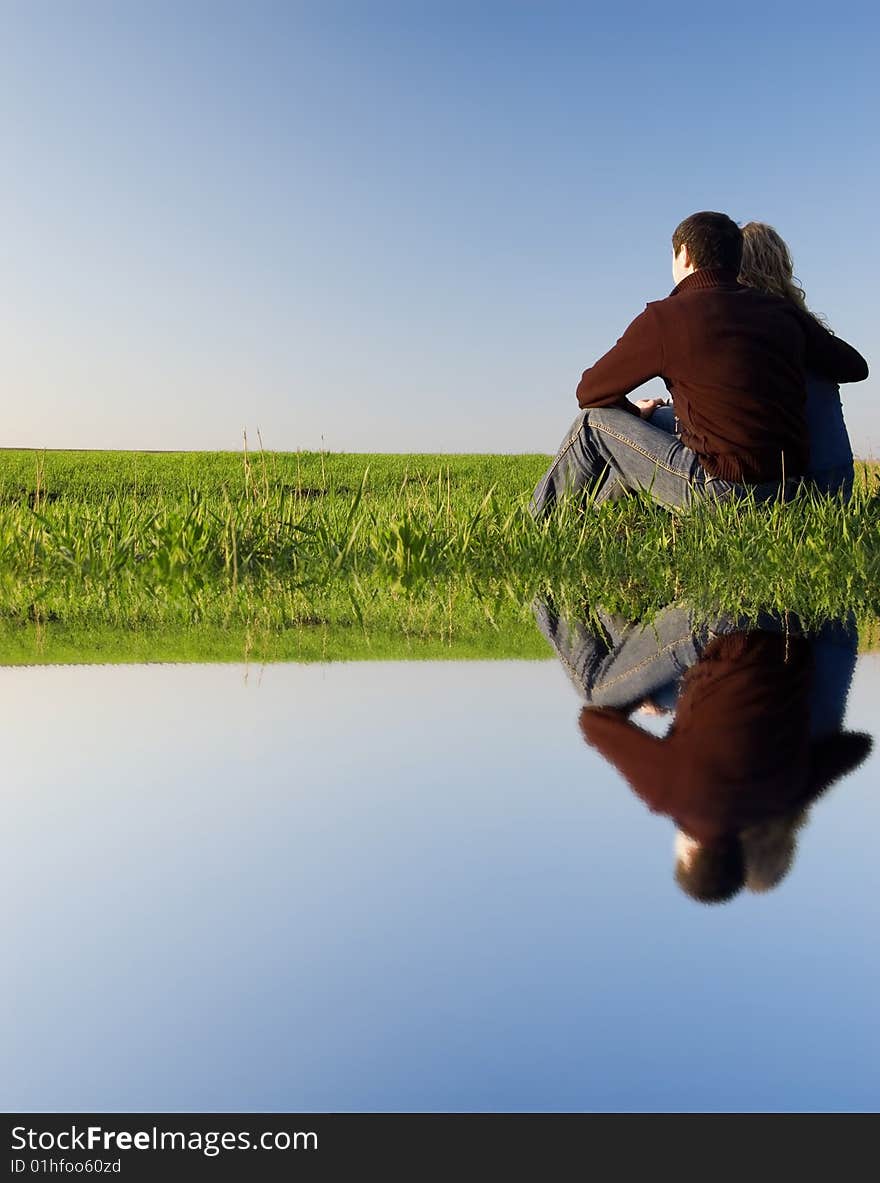 Guy embraces girl on a spring field. Near the water. Guy embraces girl on a spring field. Near the water