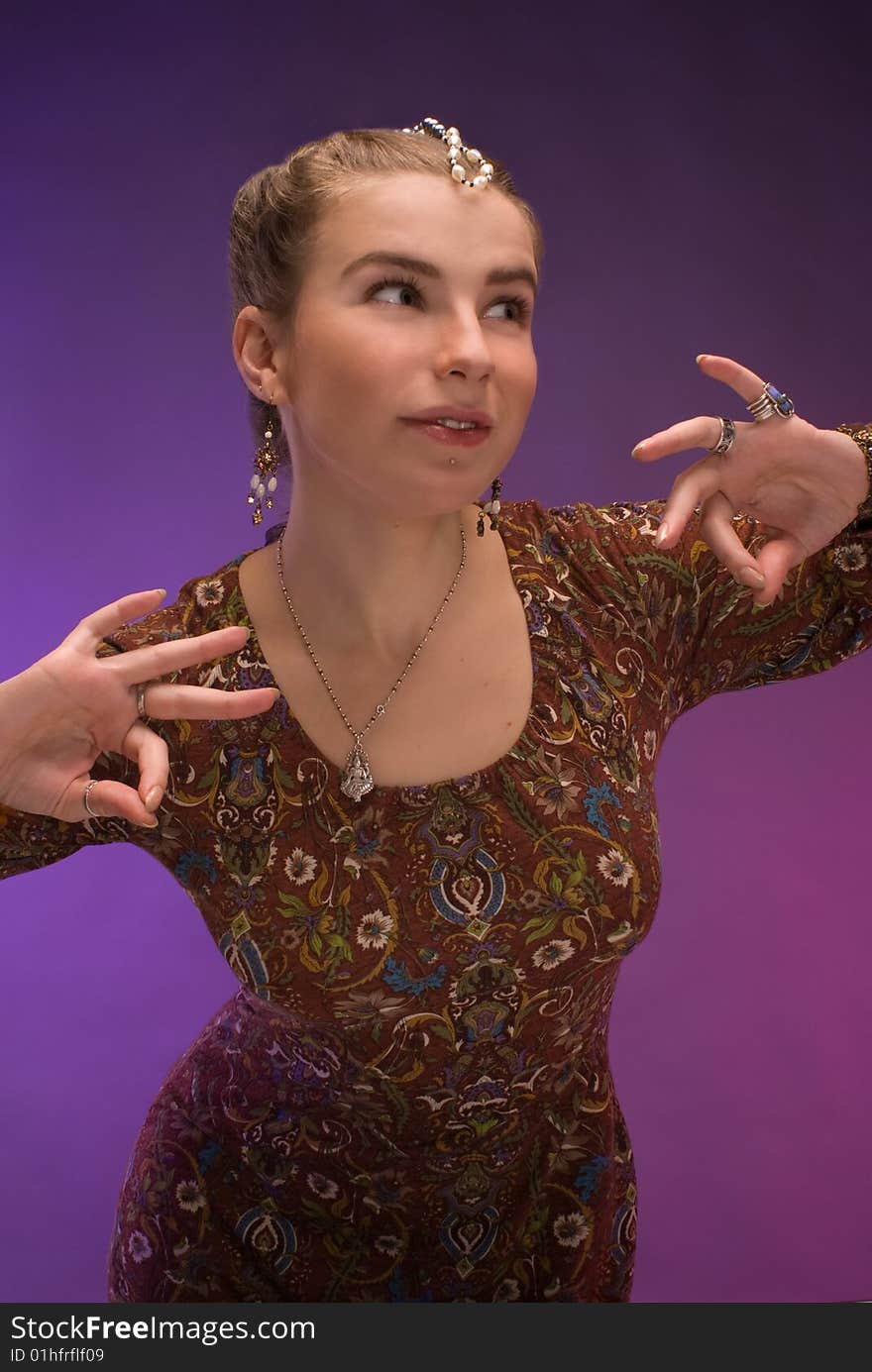 Nice young belly-dancer in ethnich indian dress against violet background