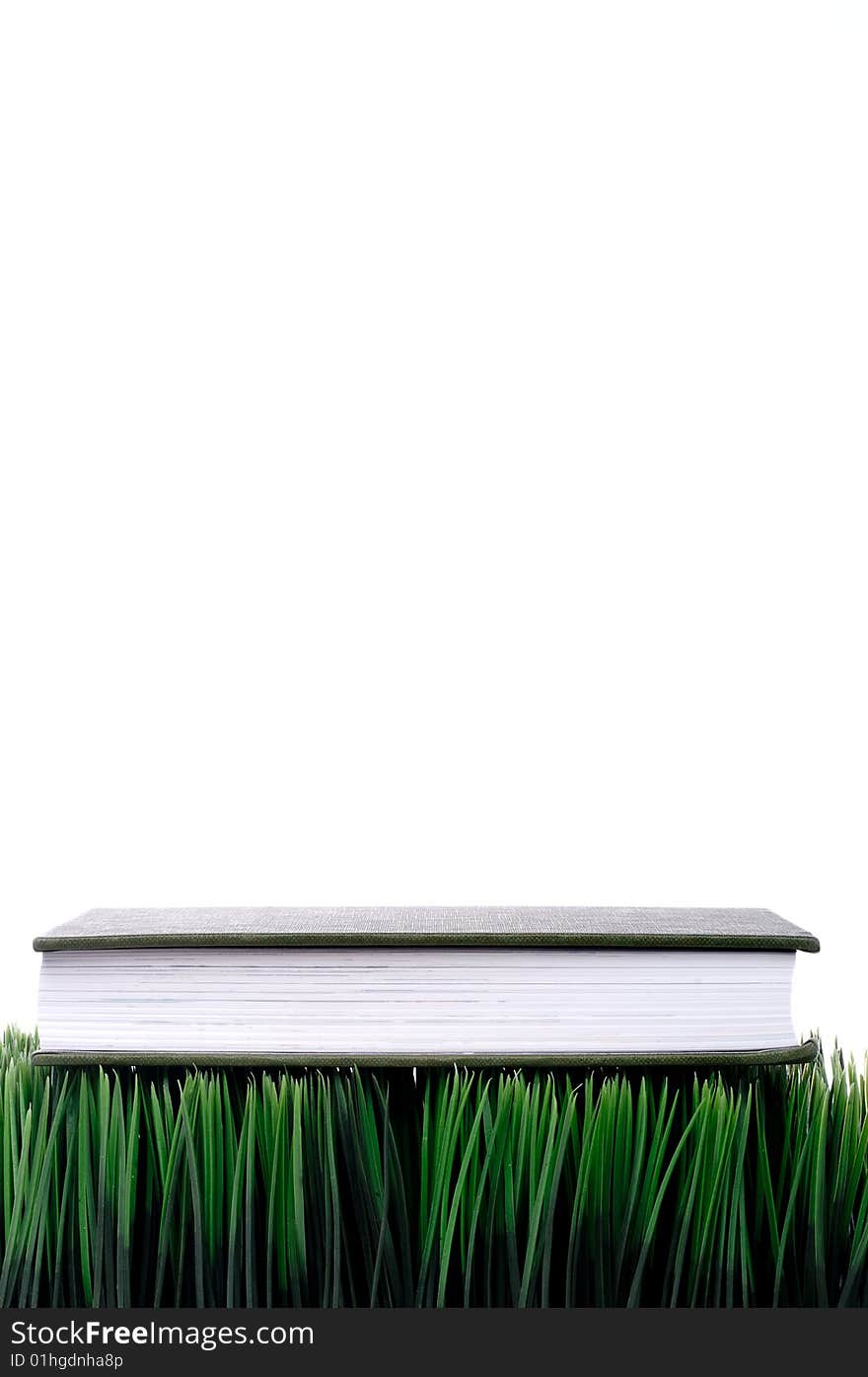 Green hardcover book sitting on grass with a white background. Green hardcover book sitting on grass with a white background