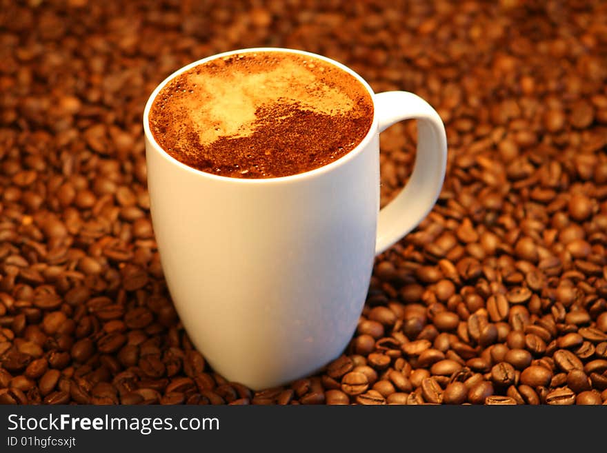 A cup of coffee with coffe beans in the background