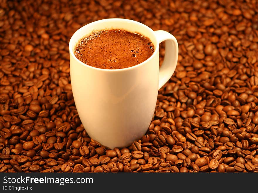 A cup of coffee with coffe beans in the background