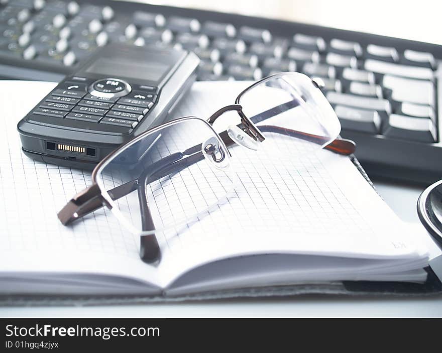 The opened notebook,  glasses and keyboard. The opened notebook,  glasses and keyboard