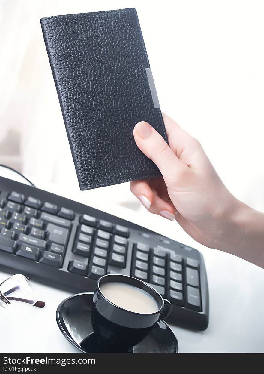 Hand whith notebook. Cup, keyboard and glass. Hand whith notebook. Cup, keyboard and glass