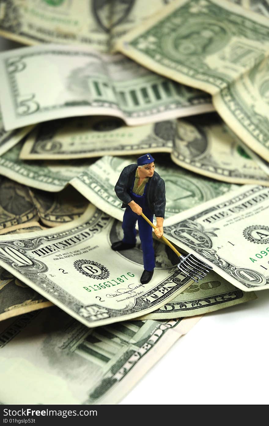 A figurine shoveling away dollar bills. A figurine shoveling away dollar bills