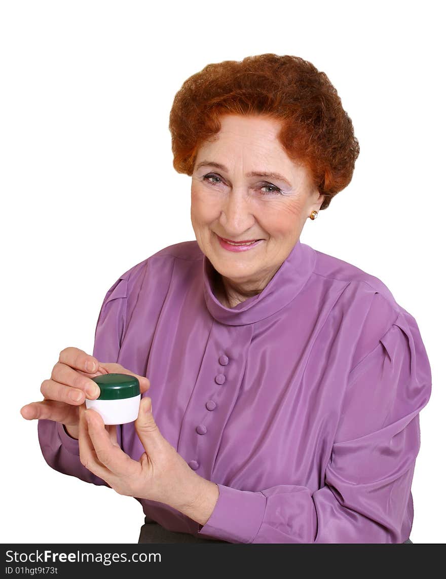 The elderly woman holds in a hand a jar with a cream. The elderly woman holds in a hand a jar with a cream