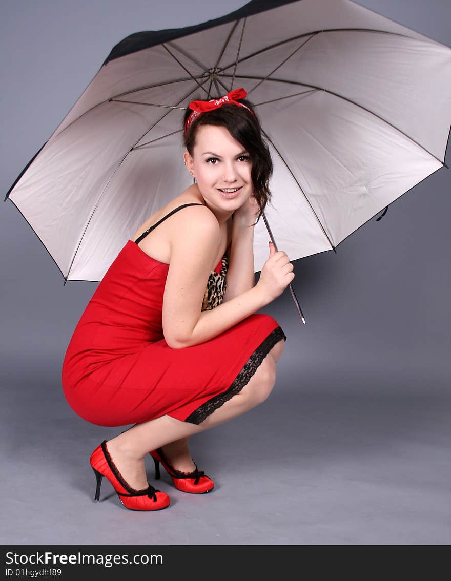 Pin-up girl sitting under umbrella in studio