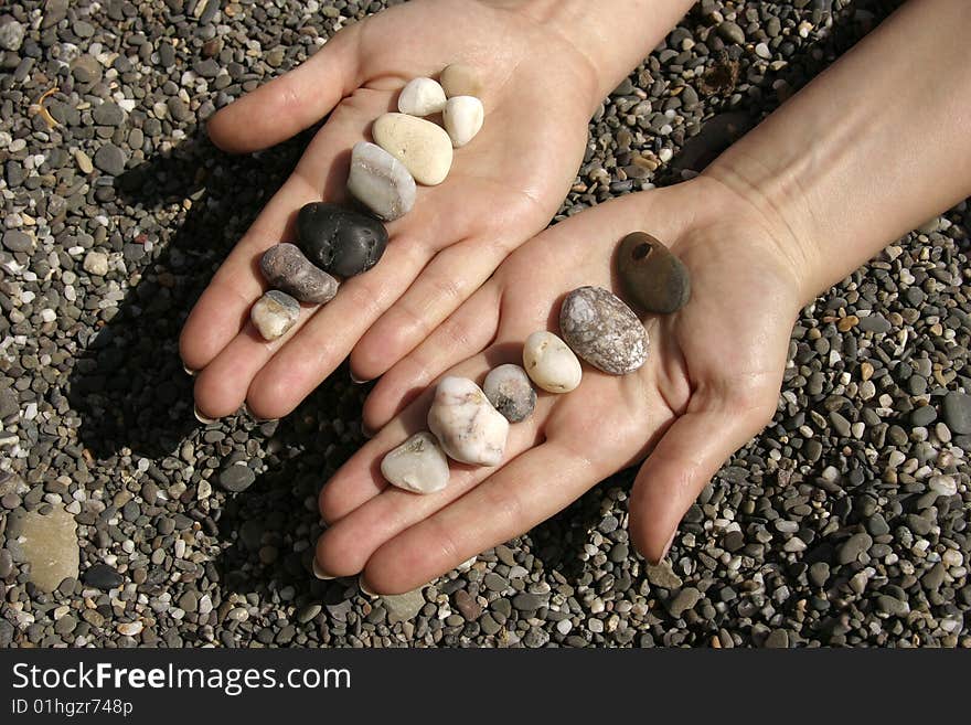 Hand with stone on summer sun beach