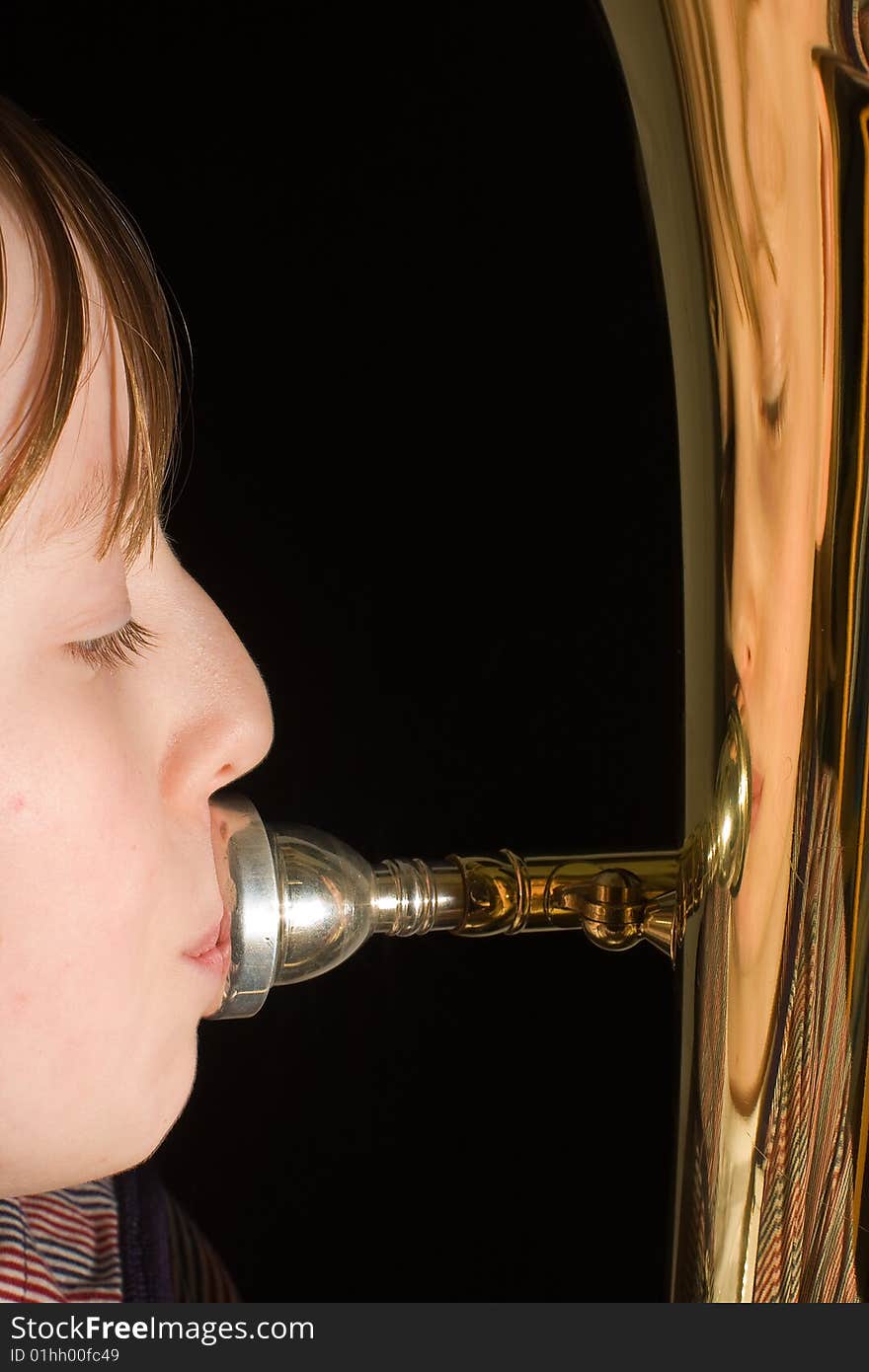 Girl playing on the euphonium with her face reflected on the shiny brass. Girl playing on the euphonium with her face reflected on the shiny brass