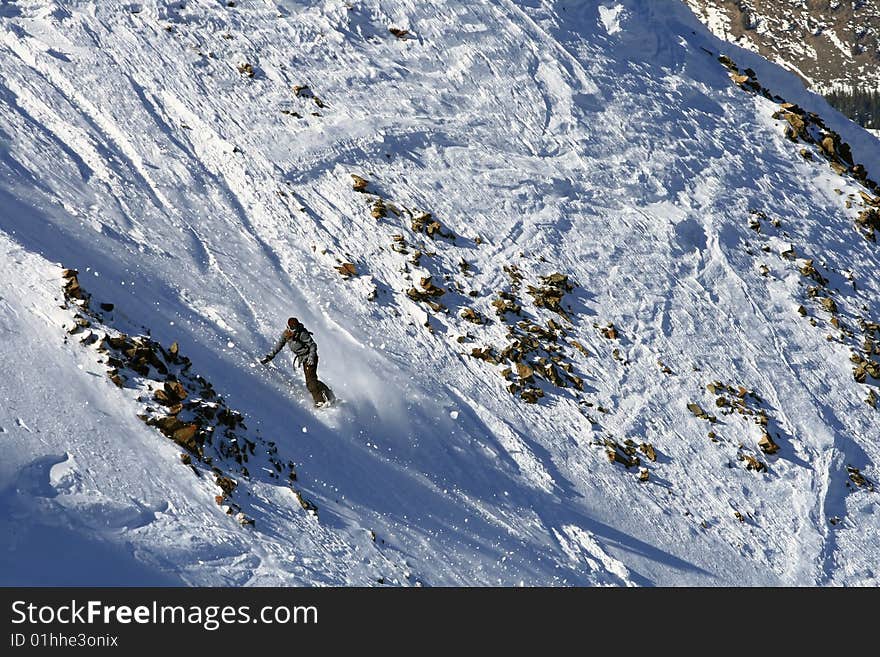 A female snowboarder descends a technical slope on a sunny day in Montana. A female snowboarder descends a technical slope on a sunny day in Montana.