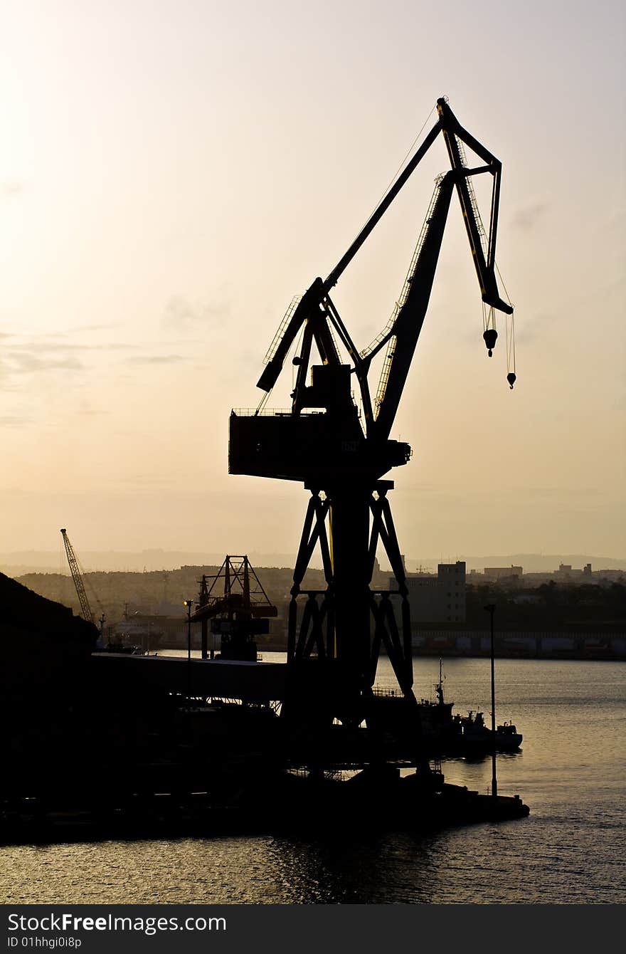 Dockyard crane next to the sea during sunset. Dockyard crane next to the sea during sunset