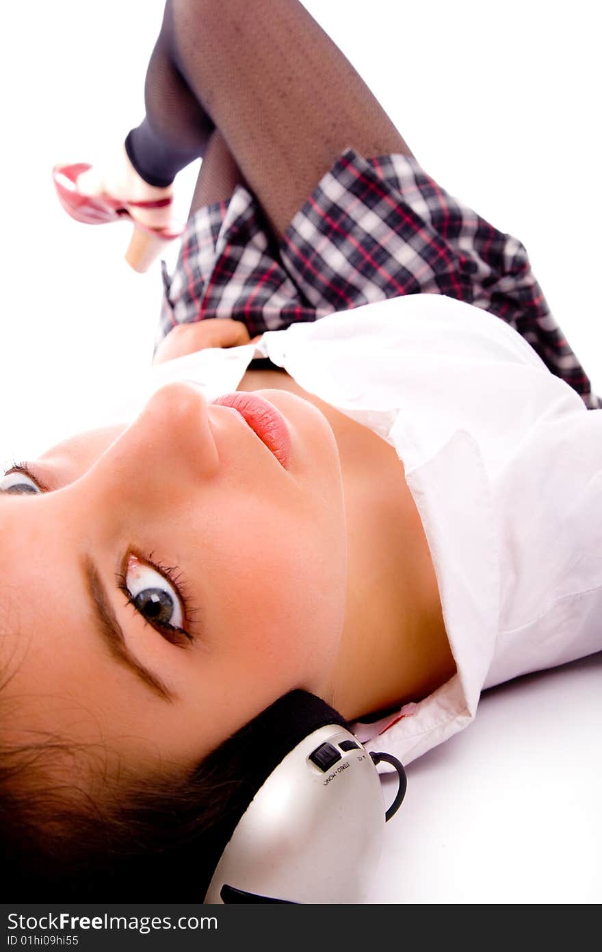 Side pose of woman on floor listening to music against white background