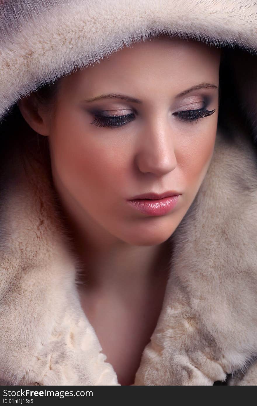 Portrait of attractive young woman wearing fur and looking away from camera