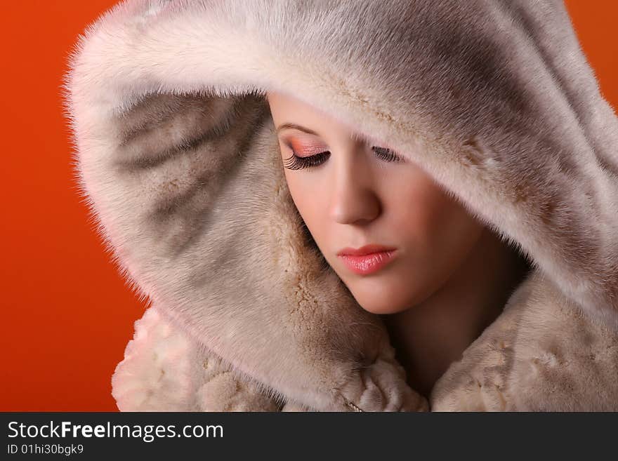 Attractive woman in fur isolated on orange background