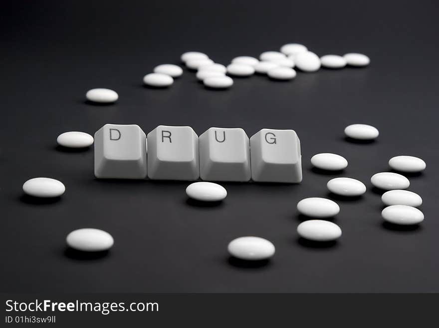 DRUG caption by keyboard keys and pile of pills on black. DRUG caption by keyboard keys and pile of pills on black