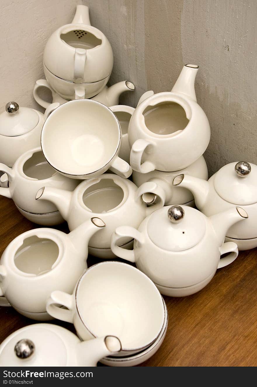 Pileup of white teapots on brown table