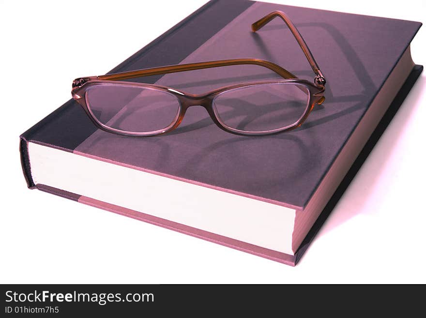 Full view of hardback book with a pair of reading glasses laying on top. Full view of hardback book with a pair of reading glasses laying on top