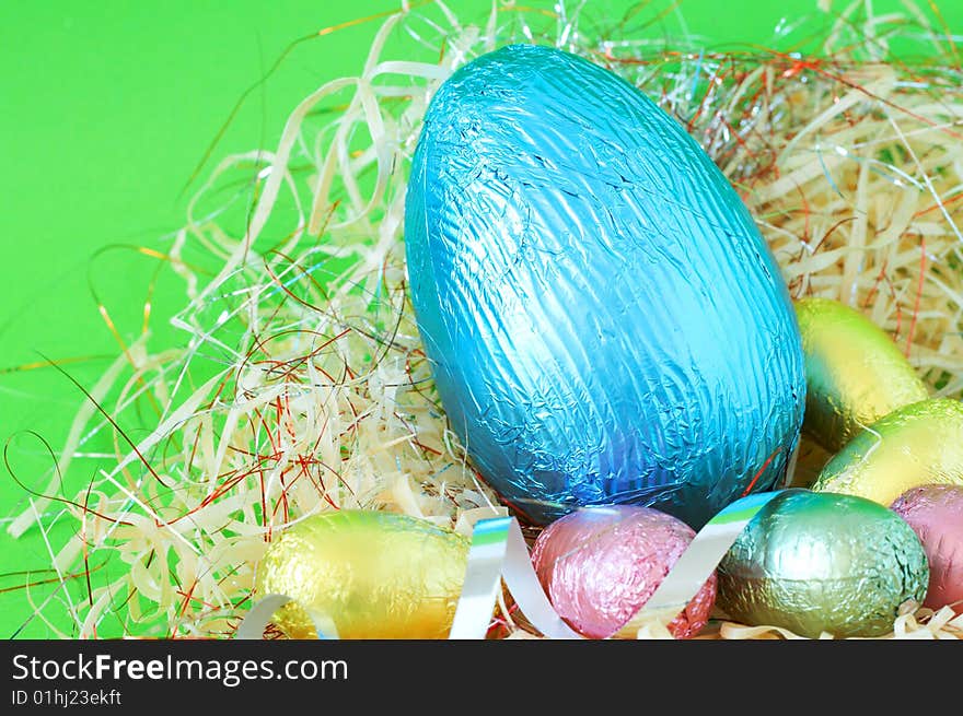 Assortment of chocolate Easter eggs wrapped in colorful paper in straw. Assortment of chocolate Easter eggs wrapped in colorful paper in straw