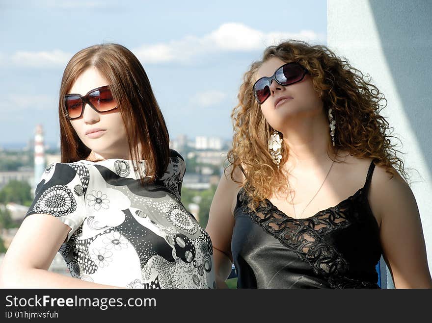 Two girls on the balcony watching the passers-by, relaxing. Two girls on the balcony watching the passers-by, relaxing