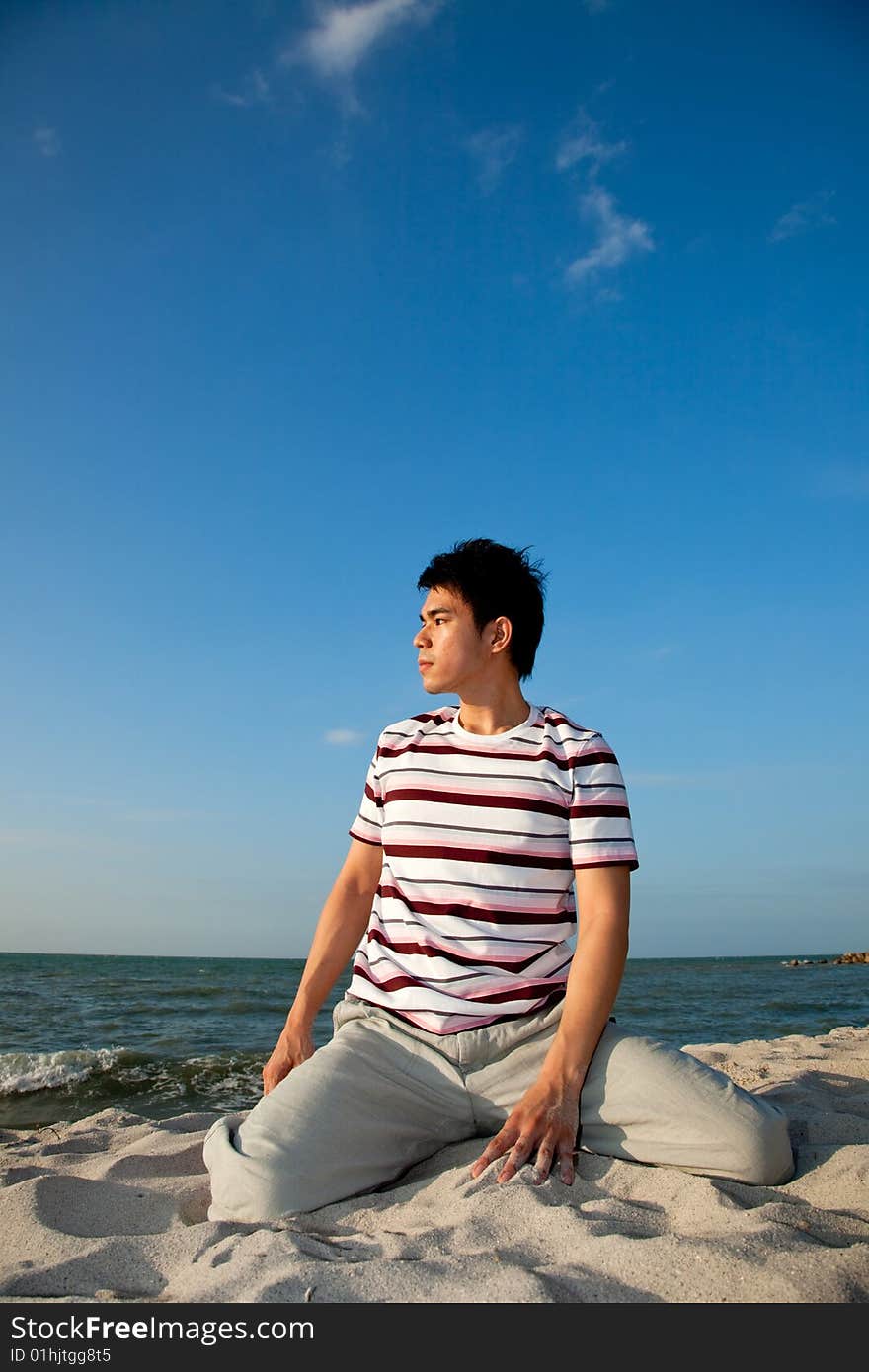 Squatting young man relaxing at the beach. Squatting young man relaxing at the beach