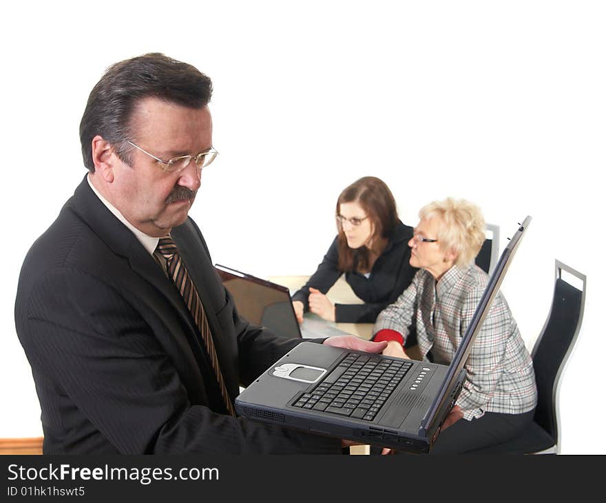 Businessman in office environment with laptop. Three people with focus on mature boss in front. Isolated over white. Businessman in office environment with laptop. Three people with focus on mature boss in front. Isolated over white.