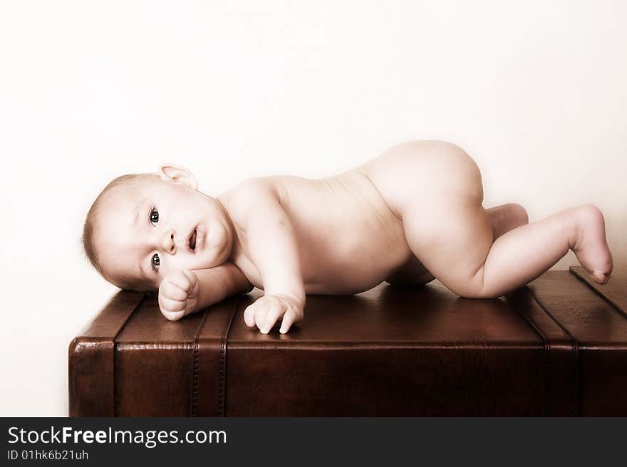 Young baby lying on his tummy on an old style suitcase