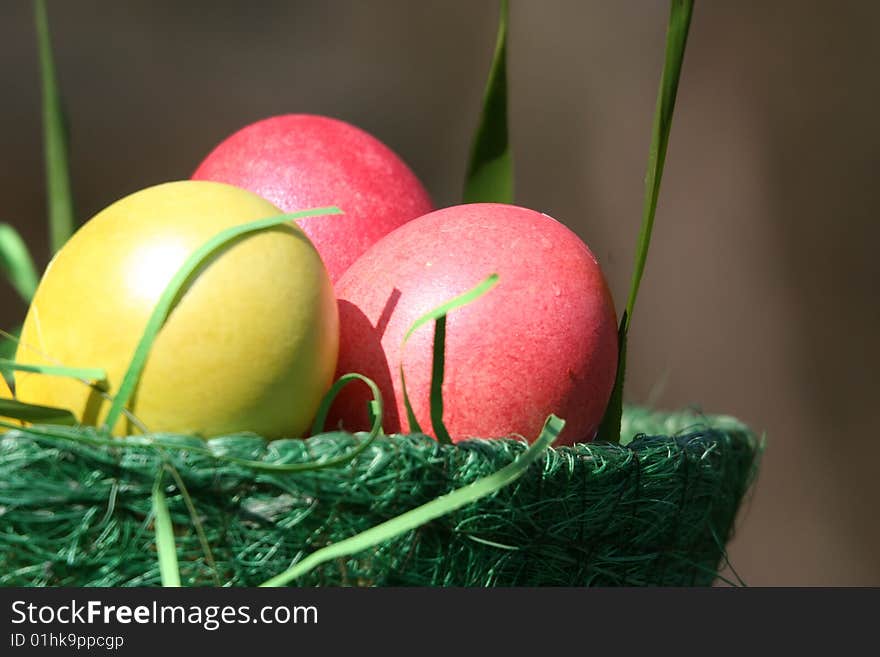 There is a green basket with easter bright yellow and pink eggs. There is a green basket with easter bright yellow and pink eggs.