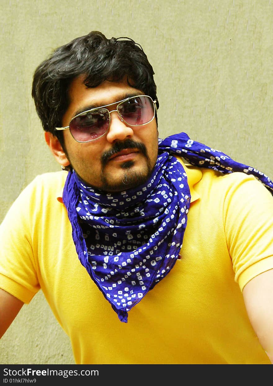 A stylish indian guy wearing a bright yellow t-shirt, posing