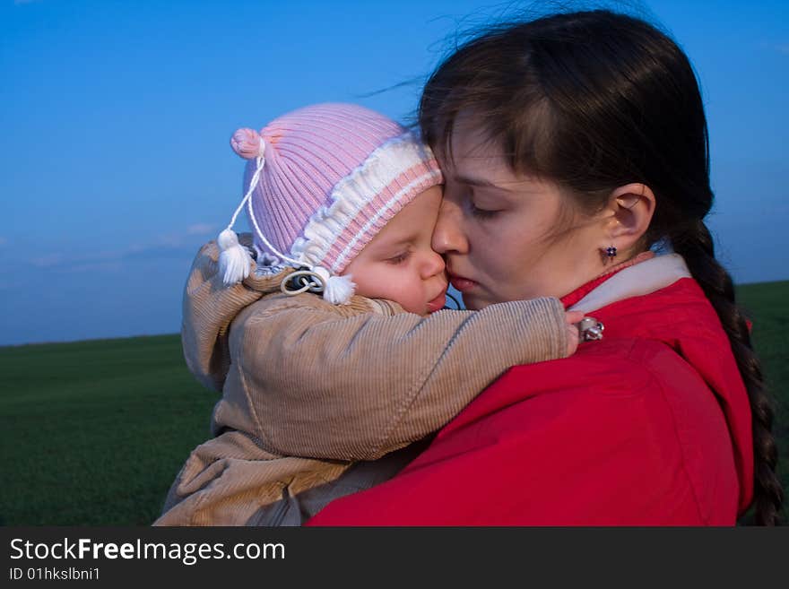 Little baby with mom on green grass and blue sky background