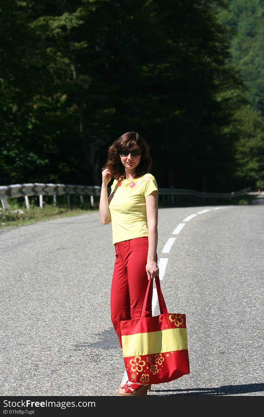 The girl is on road. She has red trousers and a yellow vest. The girl is on road. She has red trousers and a yellow vest.