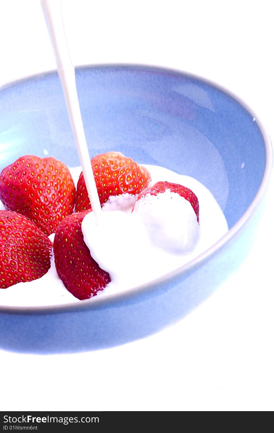 Cream being poured on to a bowl of fresh strawberries. Cream being poured on to a bowl of fresh strawberries